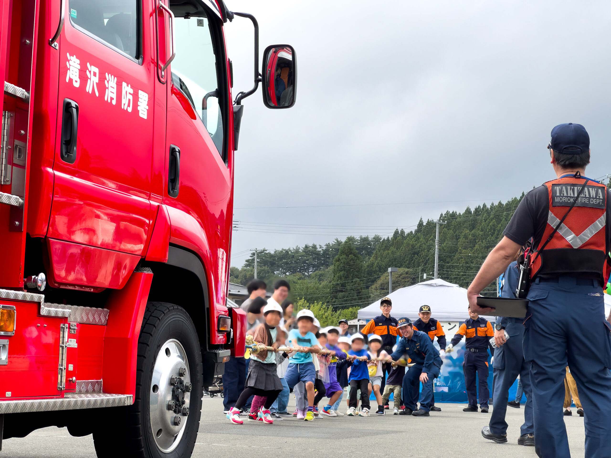 消防車の前でロープを引く子どもたち