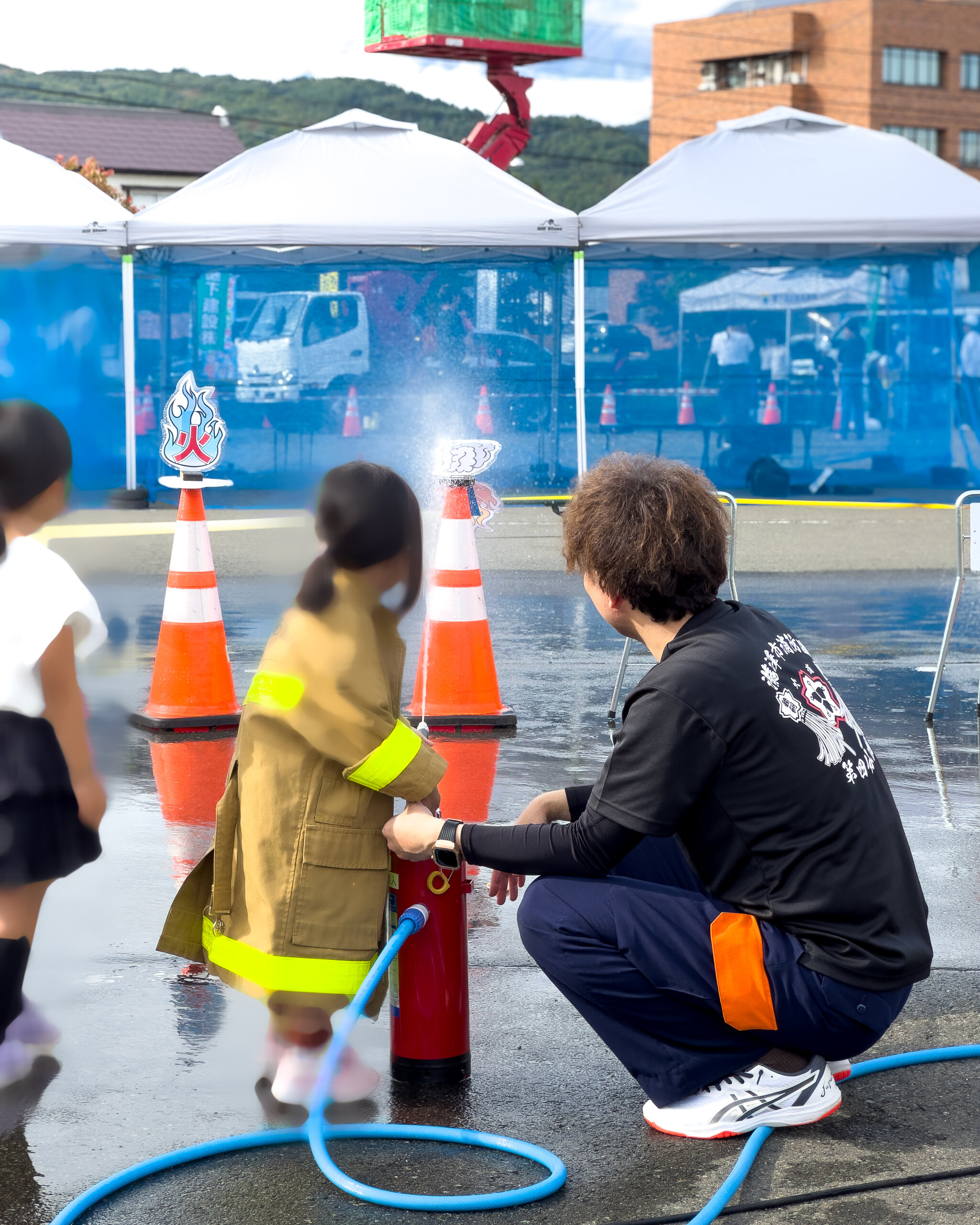 防火衣を着て放水に挑戦する子ども